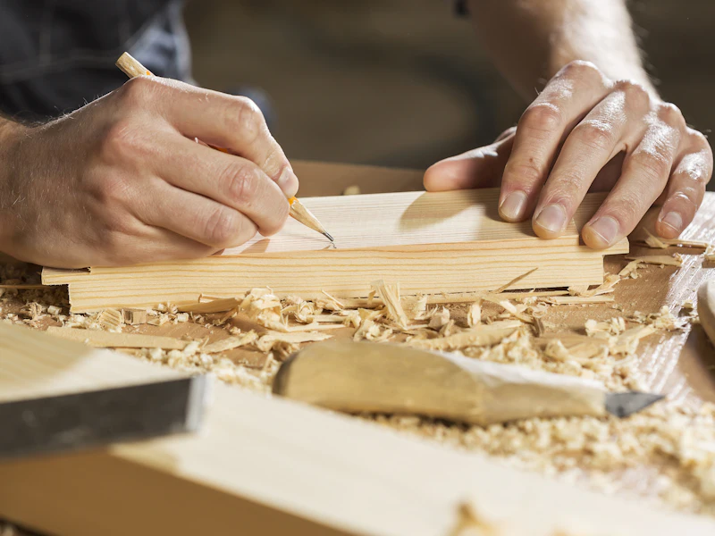 Mains d'artisan traçant une planche de bois
