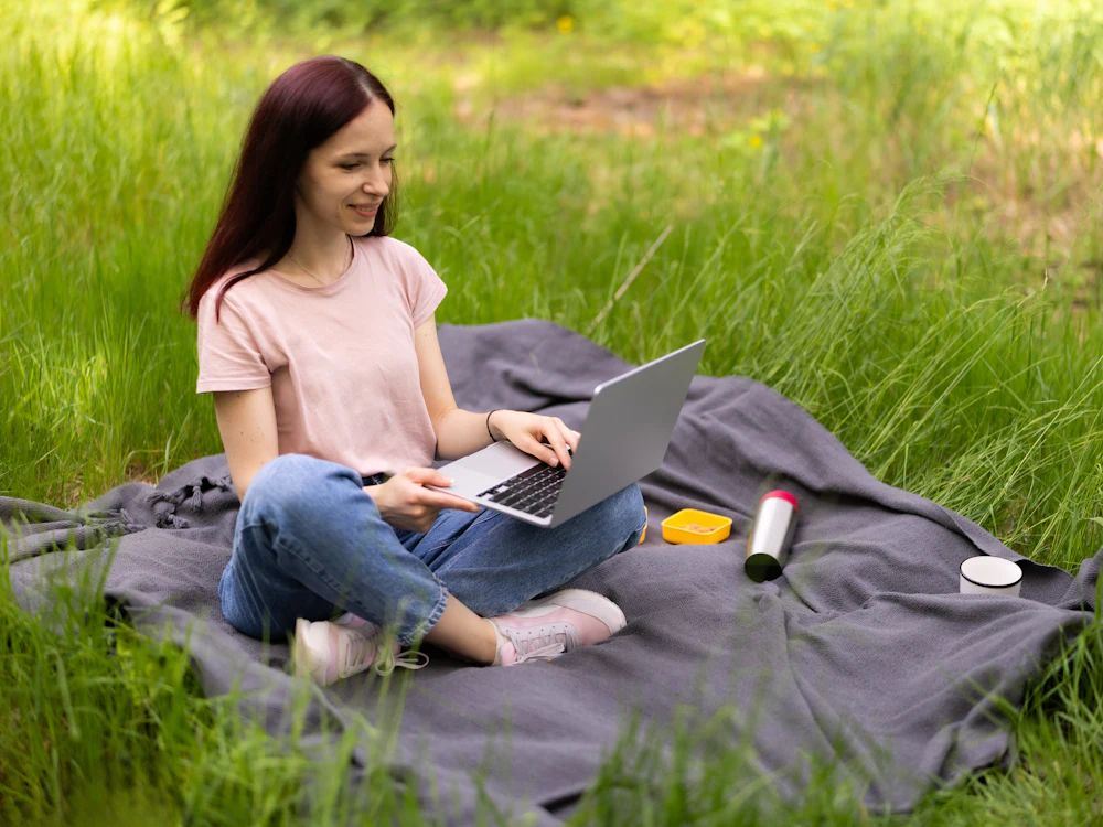 Personne travaillant sur son ordinateur dans l'herbe
