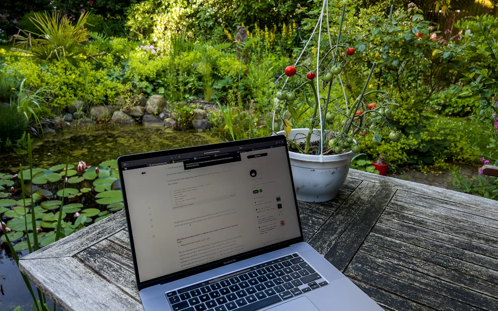 Ordinateur portable ouvert sur une table de jardin en bois